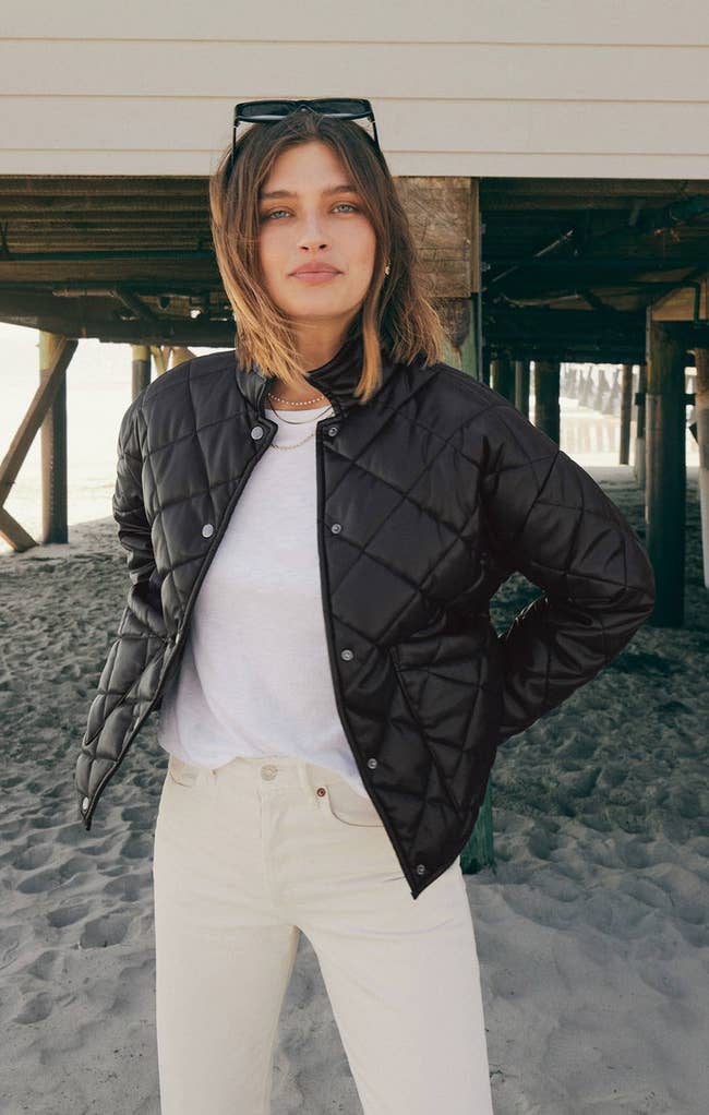 model wearing black faux leather jacket with cream colored pants