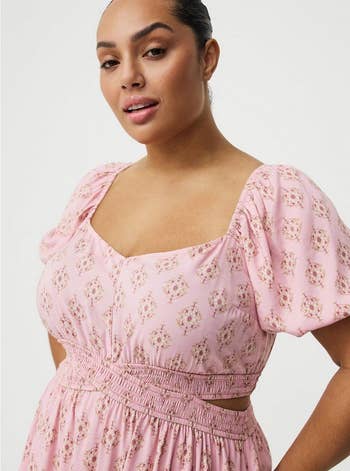 Person successful a floral-patterned formal with puffed sleeves, looking confidently astatine the camera