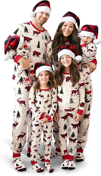 a family in matching holiday pajamas with moose and christmas trees on them