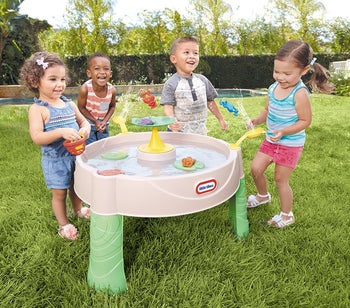 Children flinging toy frogs in the water table