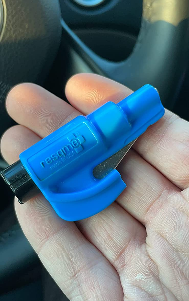 Reviewer holding their two-in-one car window breaker and seatbelt cutter in their hand