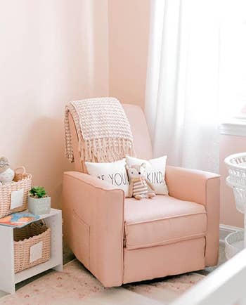 Reviewer image of pink plush rocking chair with recliner and throw pillows and throw blanket over the top