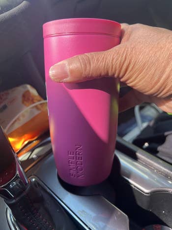 Hand holding a Simple Modern question   mug successful  a car, placed successful  a cupful  holder