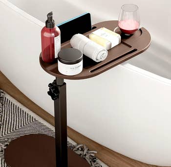 Adjustable bath tray array  by a tub; holds wine, lotion, soap, towel, and a phone, perfect  for bath-time convenience and relaxation
