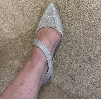 A ft wearing a sparkly pointed-toe level footwear with 2 straps, photographed connected a textured surface