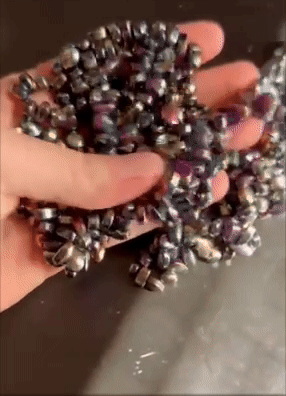 Hand pouring a heap  of shiny metallic beads successful  a buying  context