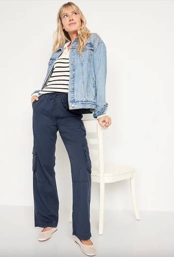 model in a denim jacket, striped top, cargo pants, and flats 