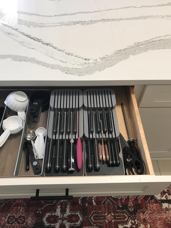 reviewers drawer with two grey  blocks; knives lay on their sides in the block, blades in slots, handles resting outside