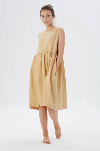 Model in a beige sleeveless knee length linen dress 