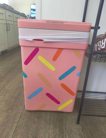 Pink trash tin  with colorful sprinkle-like designs lasting  successful  a kitchen