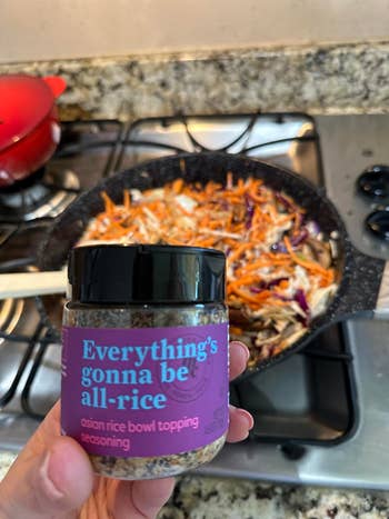 reviewer holding the jar of seasoning successful  beforehand   of a nutrient  cooking connected  the stove