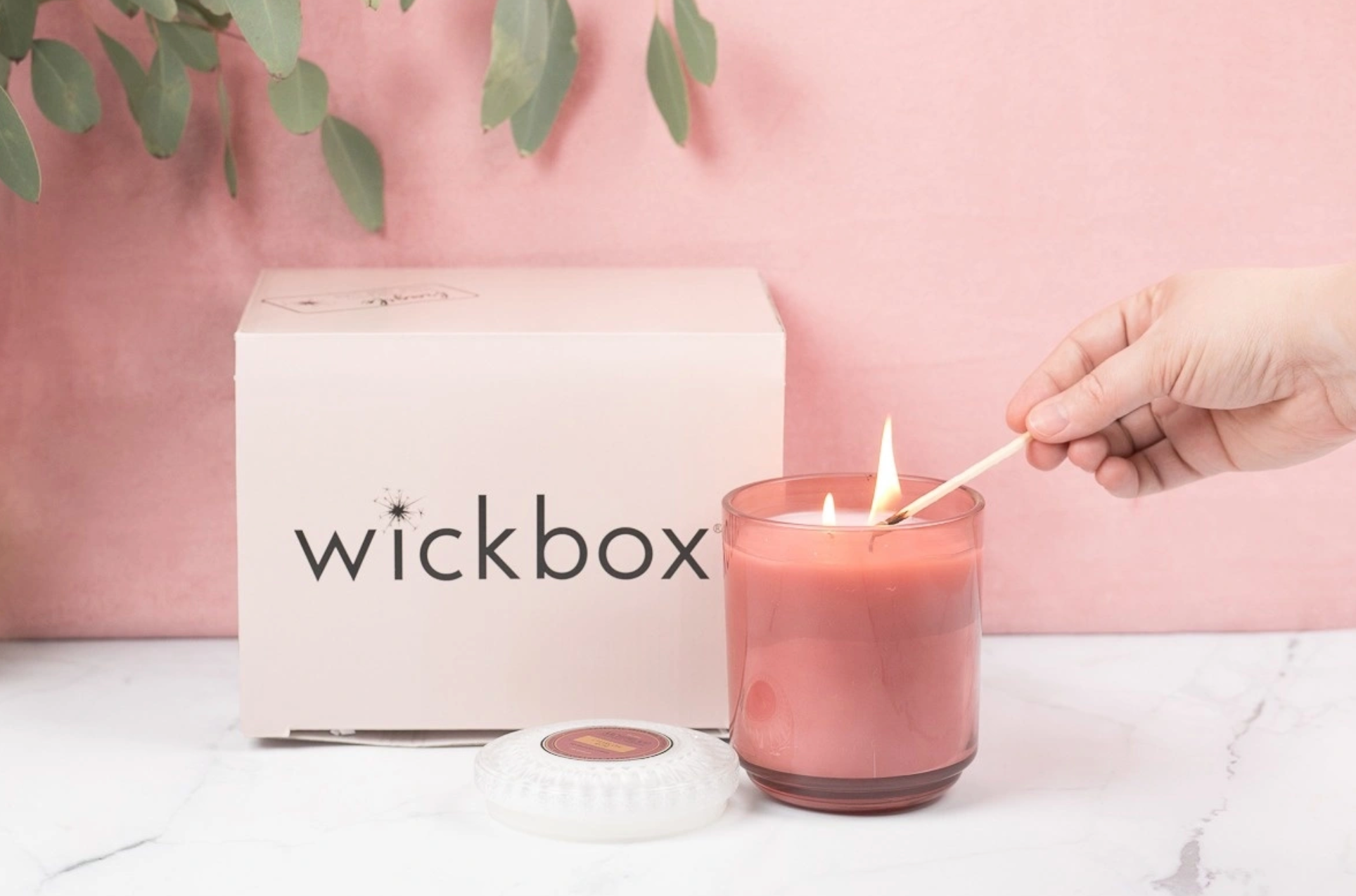 person lighting candle with wickbox box in the background