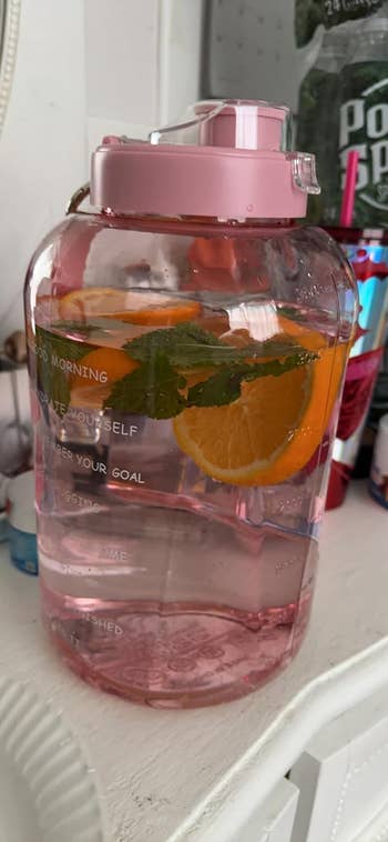 reviewer's water bottle in pink with oranges in the water