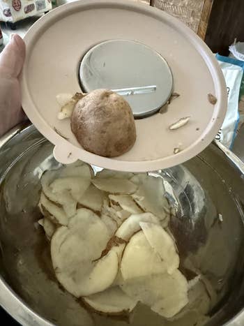 A idiosyncratic   uses a mandoline slicer to thinly portion    potatoes into a mixing bowl, illustrating room  mentation  and cooking tools