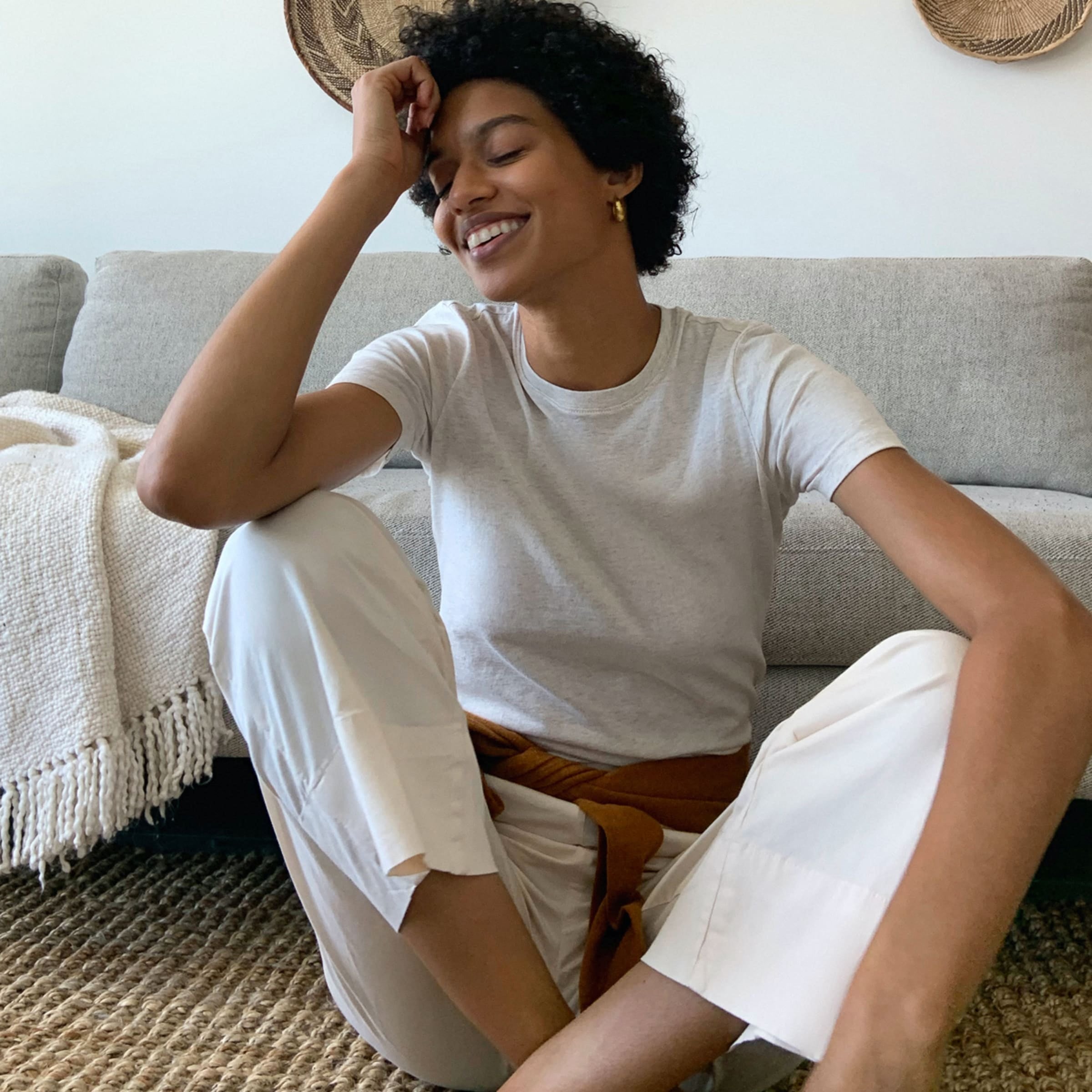a model sitting on the floor wearing the heather gray organic cotton crew top