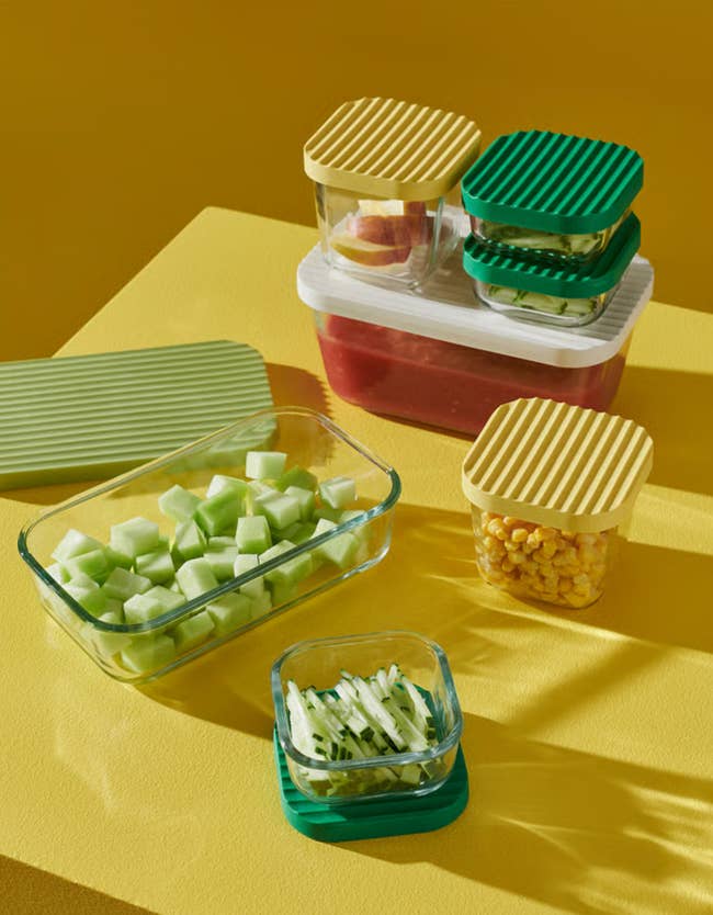 Various solid  retention  containers with colorful ribbed lids, filled with fruits and vegetables, are displayed connected  a table