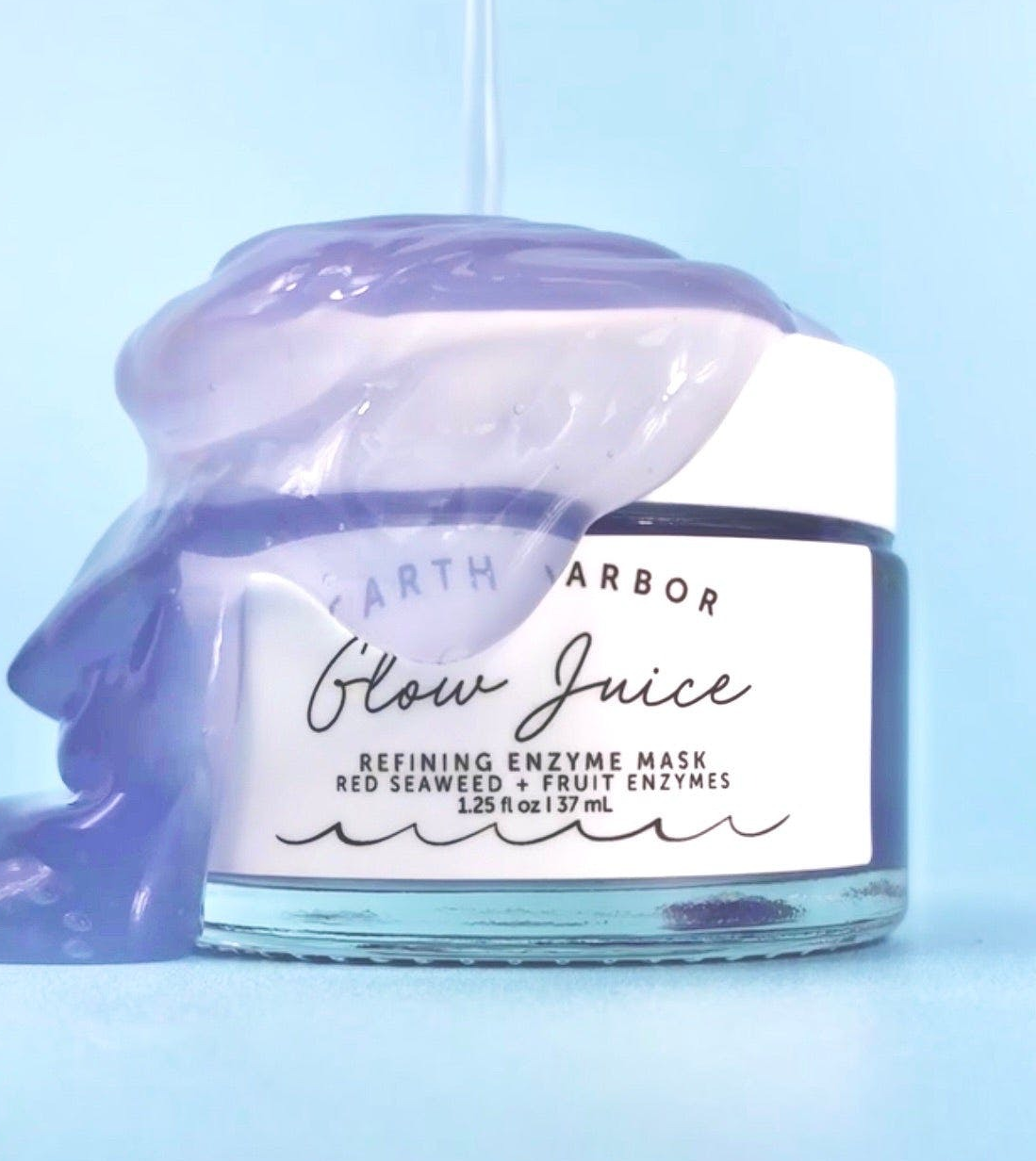 the blue jar of Glow Juice with some of the purple liquidy product being poured over the top