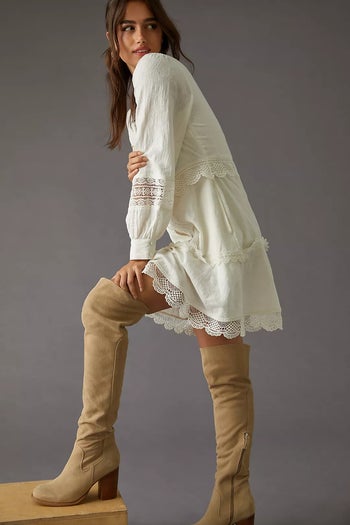 model wearing sand over-the-knee boots with a lace-trim dress