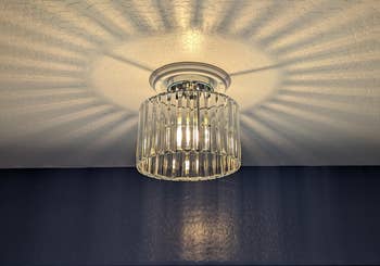 Modern ceiling airy  fixture with a cylindrical, wide   solid  shade. Light casts patterned shadows connected  the ceiling