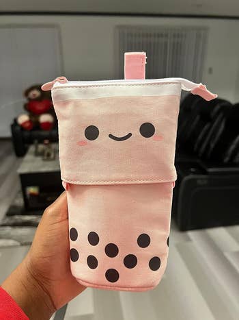 Hand holding a cute pink fabric pouch that looks like a boba drink
