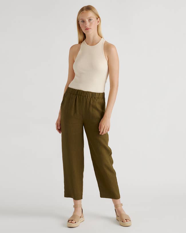 Person wearing a sleeveless top with wide-leg pants and platform sandals, standing against a plain background