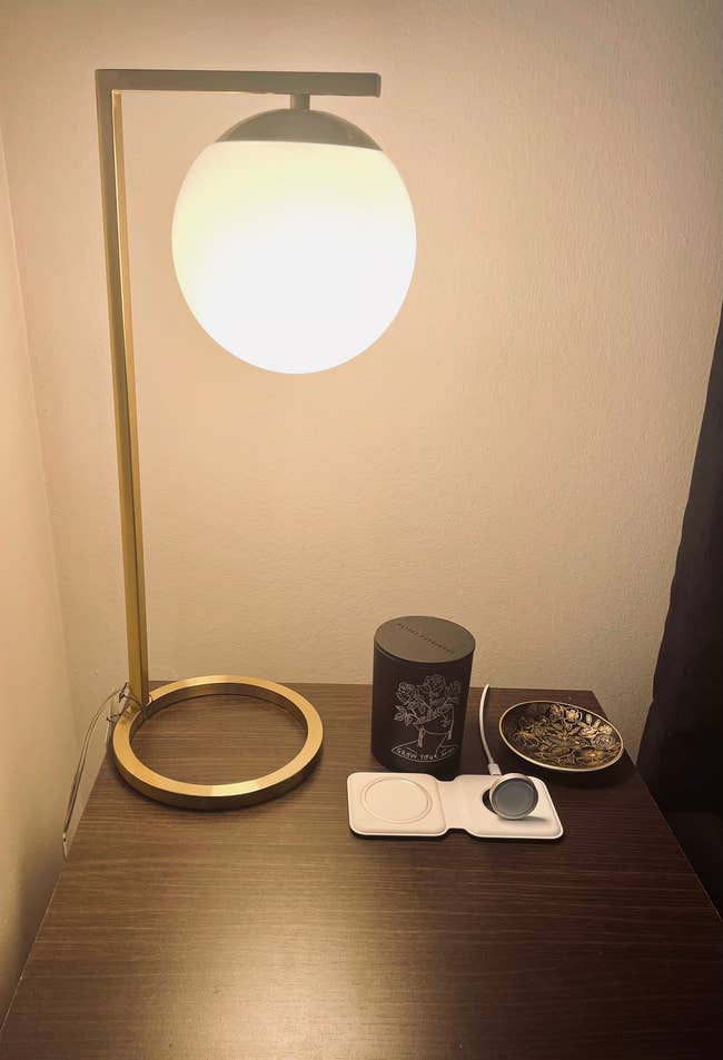 gold lamp with circular bulb on a nightstand
