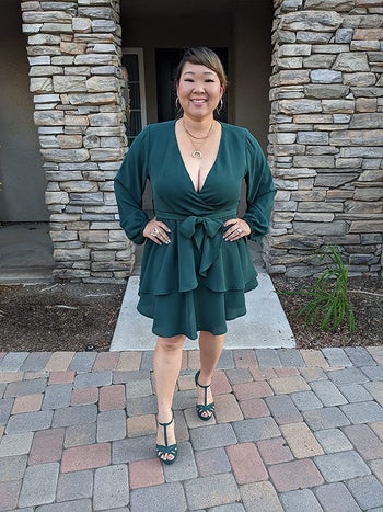 Reviewer is wearing the wrap dress in a emerald green color