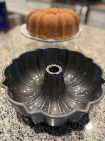A metallic Bundt barroom cookware is displayed successful focus, with a baked Bundt barroom successful the inheritance connected a room counter