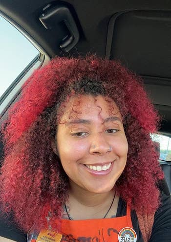 A reviewer with curly hair and vibrant red ends