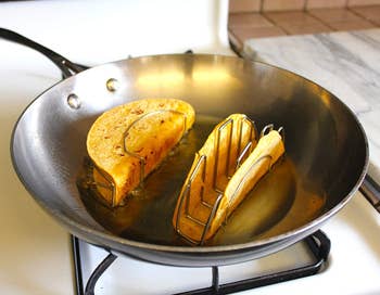 Two tortillas in a metal stand cooking in a saucepan 