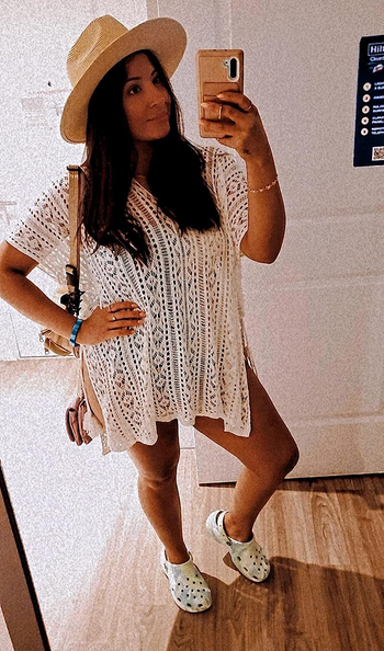 reviewer in short sleeve v-neck cream open knit cover-up styled with hat and crocs