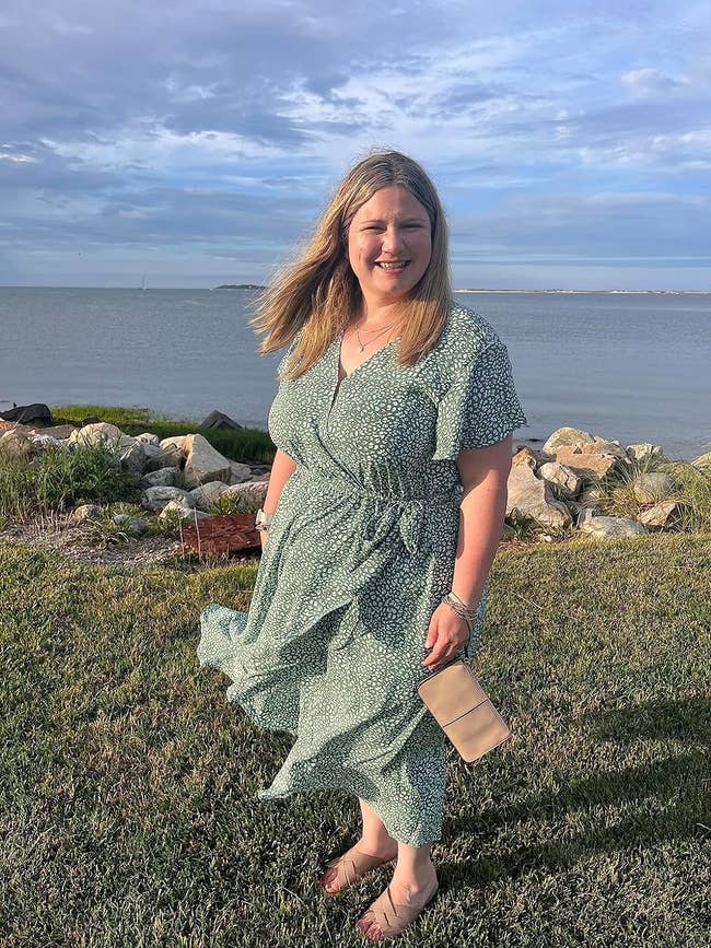 reviewer in a wrap dress with a clutch, by the sea