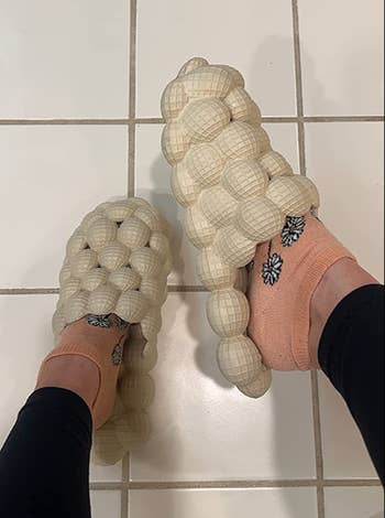 reviewer wearing off white slide on sandals with a bubble texture