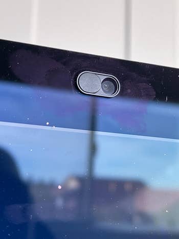 a reviewer's open black camera cover attached to a laptop