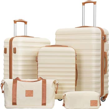 A five-piece cream-colored luggage set with brown accents, featuring three rolling suitcases of different sizes, one duffel bag, and one zippered pouch