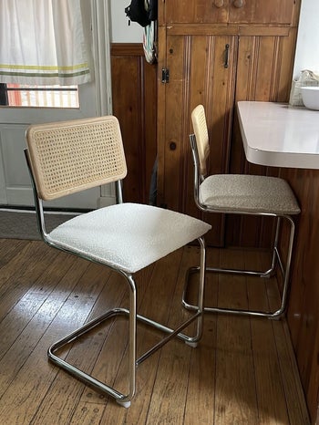 two of the rattan bar stools with white cushions next to a bar