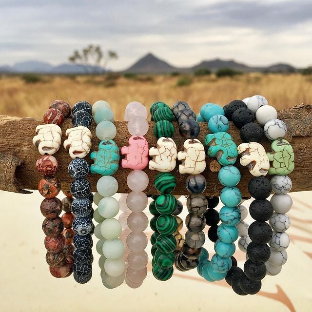 a line up of beaded bracelets in different colors each with an elephant charm