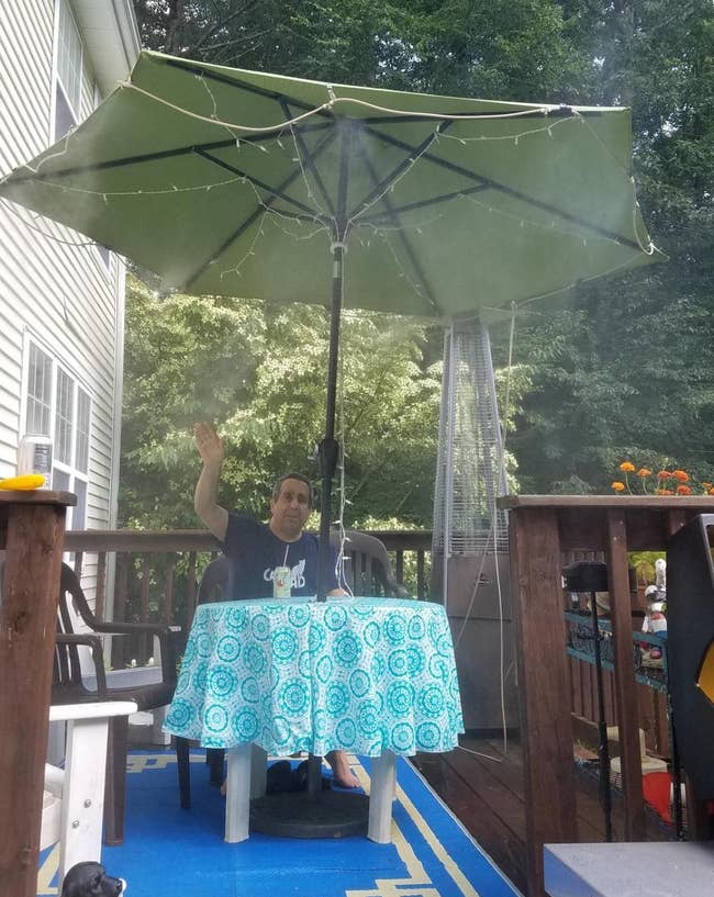 Person sitting connected a platform nether a ample umbrella with a h2o mister