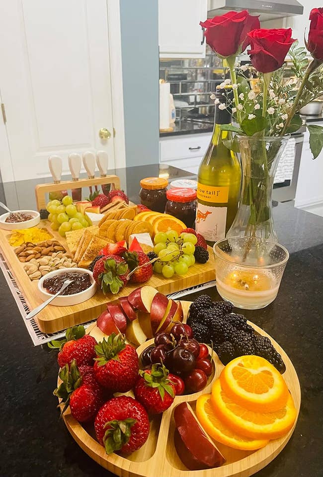 Charcuterie committee  with fruits, nuts, and jams connected  a table. Wine vessel  and roses successful  a vase nearby, creating a cozy eating  setup