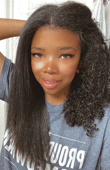 reviewer with half of their hair natural and curly, and the other half blow-dried straight using the hot air brush