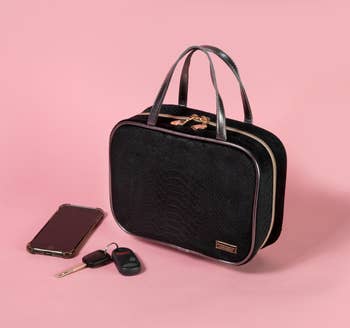 black zip-around toiletry bag, phone and keys nearby