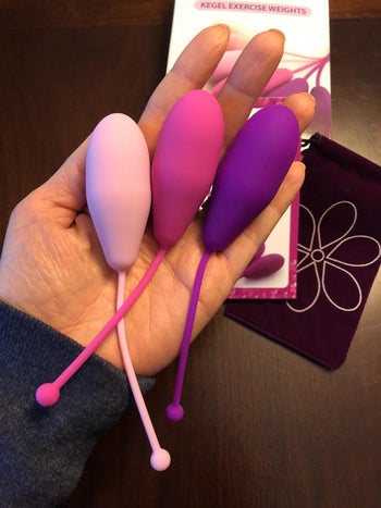 reviewer's hand holding three kegel weights