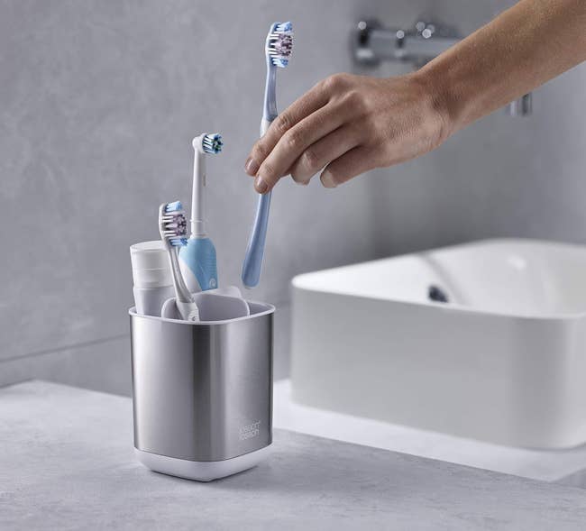Hand placing a toothbrush successful a sleek, modern toothbrush holder connected a bath antagonistic adjacent to a sink