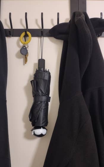 Jacket, umbrella, and keys with a holder hang on wall hooks, suggesting essential items for daily use or commuting