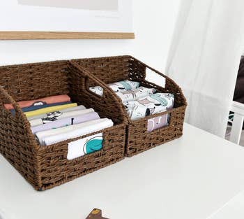 two dark brown woven baskets holding baby supplies
