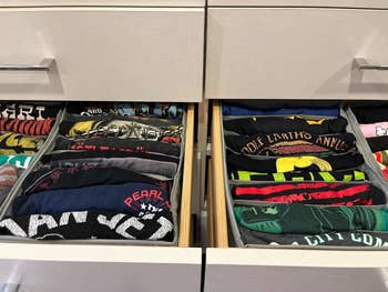 Dua laci terbuka tertata rapi dengan kaos bergambar lipat yang menampilkan berbagai desain