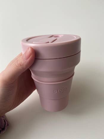reviewer showing the pink collapsible coffee cup full expanded