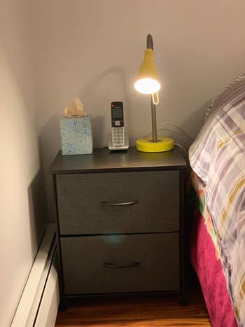 reviewer photo of gray fabric drawer nighstand next to bed