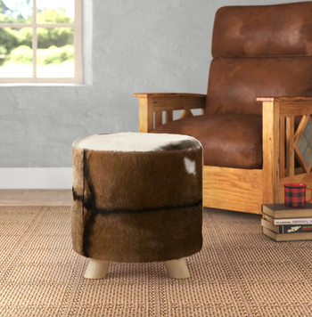 lifestyle photo of round cowhide leather ottoman with legs