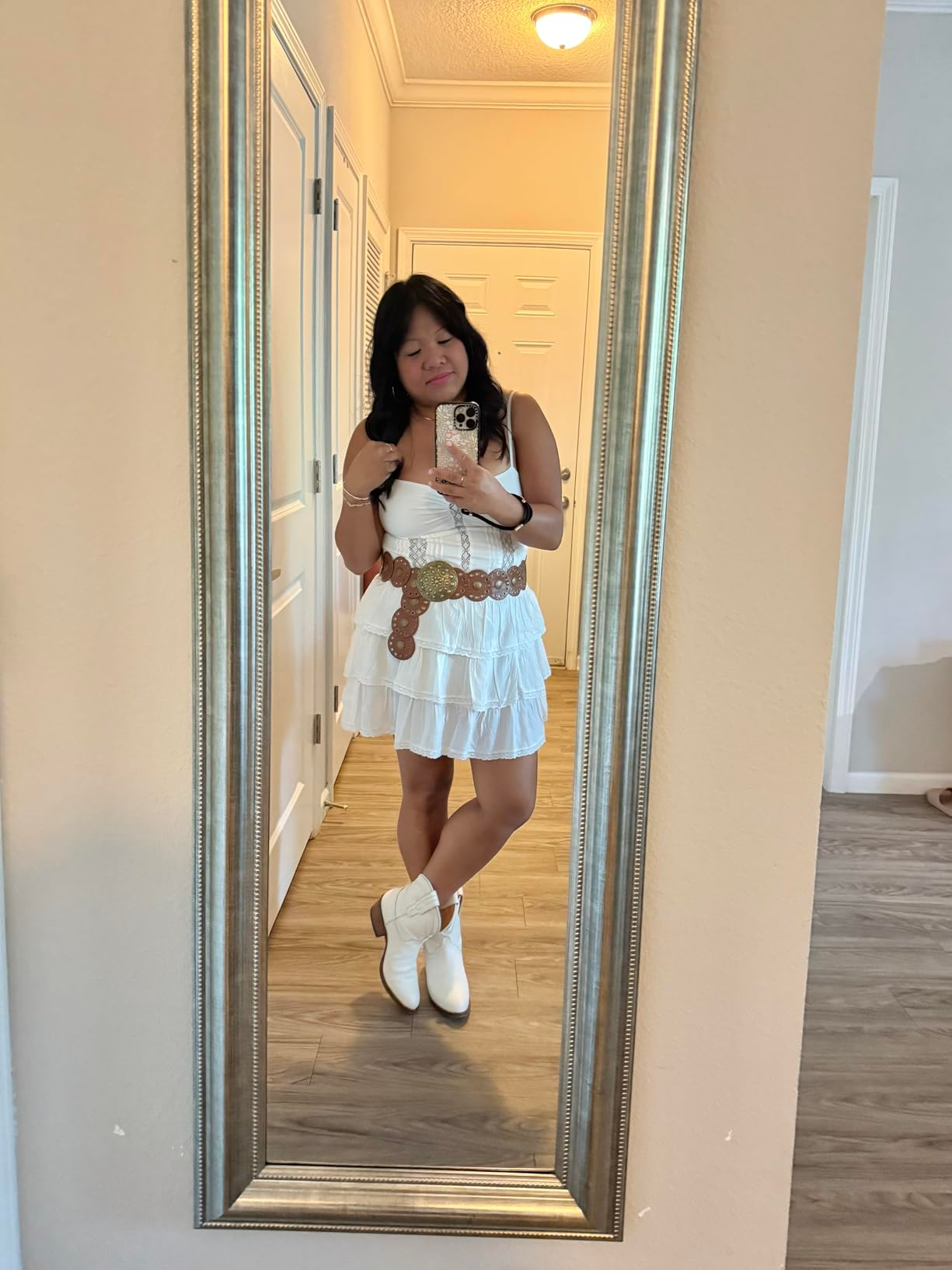 A idiosyncratic   stands successful  a reflector  selfie wearing a tiered achromatic  formal  with a wide   loop  and cowboy boots